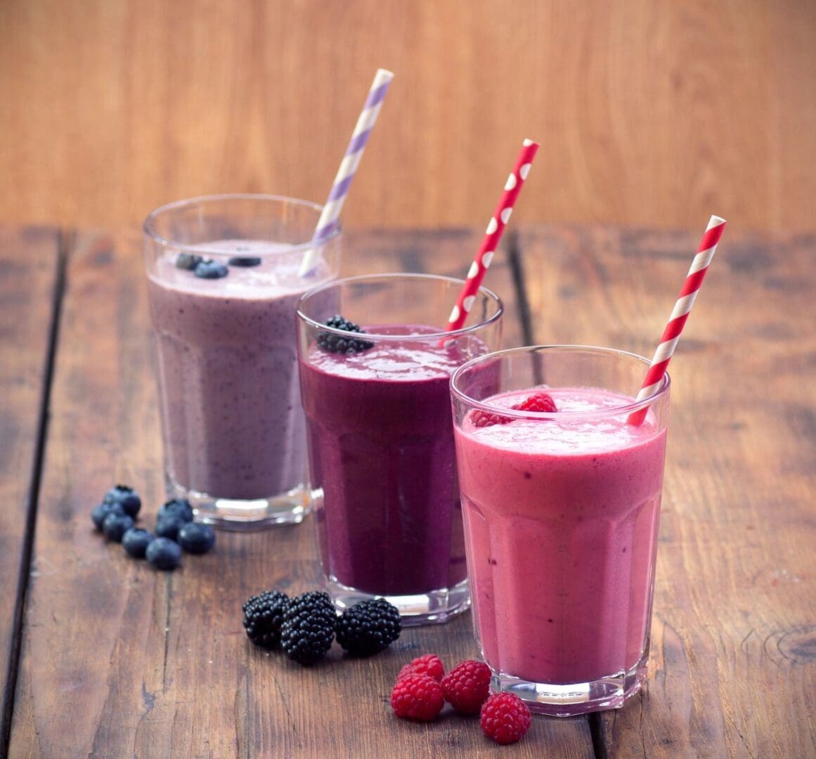 Three glasses of smoothies are sitting on a table.